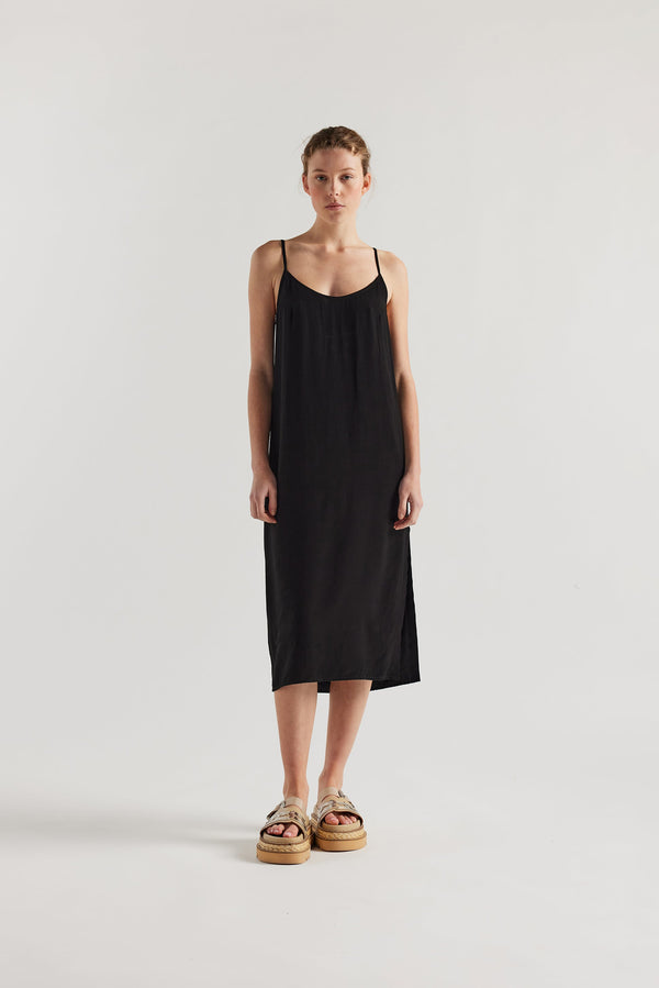 Front view of model in black Mid-length slip dress with straight neckline and relaxed silhouette