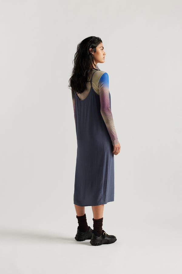 Back Angle of female model indigo blue Mid-length slip dress with straight neckline and relaxed silhouette