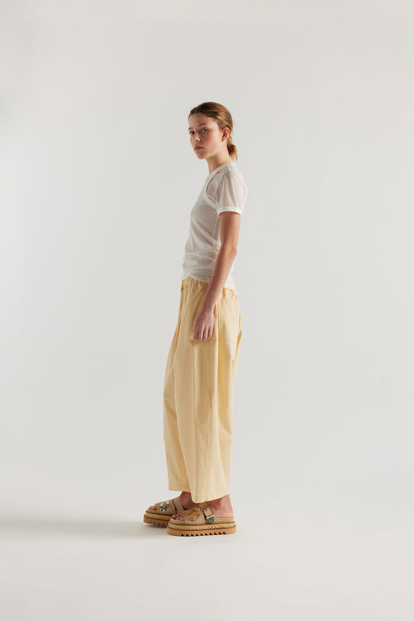 Side view on female model of the slim-fit sheer knit tee with ringer neckline in White. 