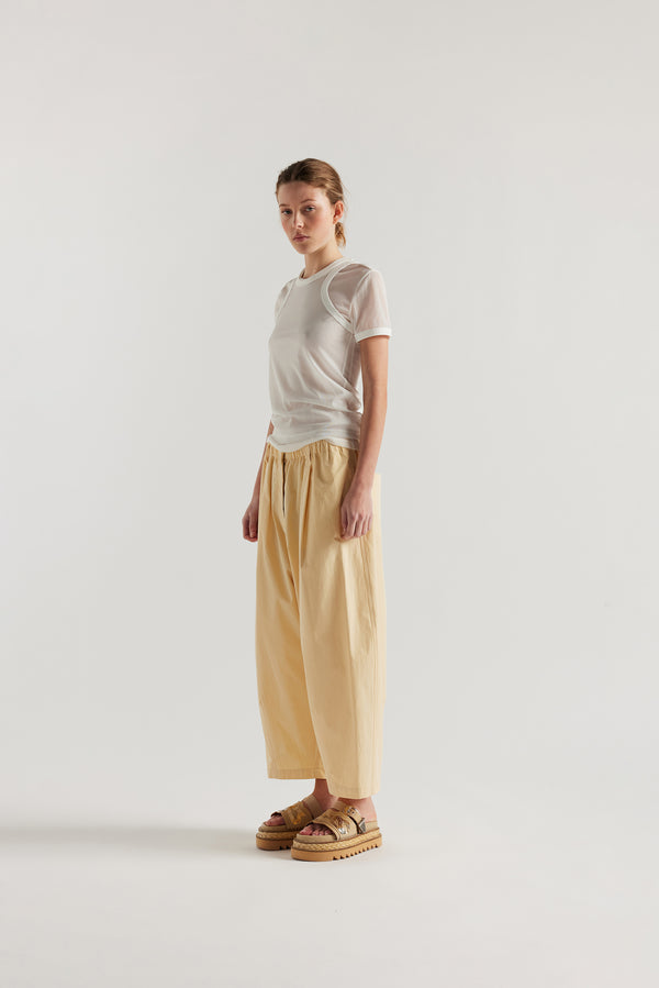 Front view of the model in the Factor Pleat Pant Buttermilk yellow. A relaxed silhouette defined by an encased elastic waistband. 