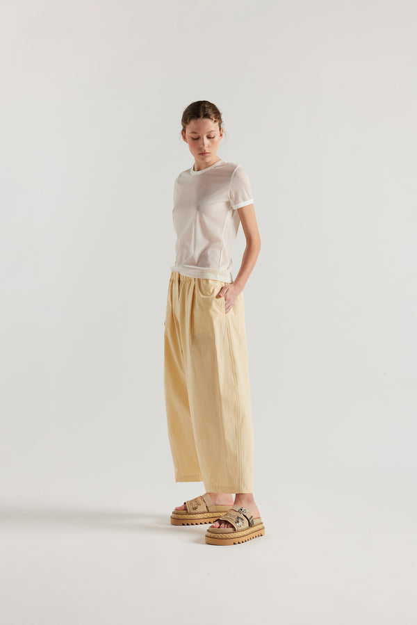 Front of female model wearing the Factor Pleat Pant Buttermilk yellow. A relaxed silhouette defined by an encased elastic waistband. 