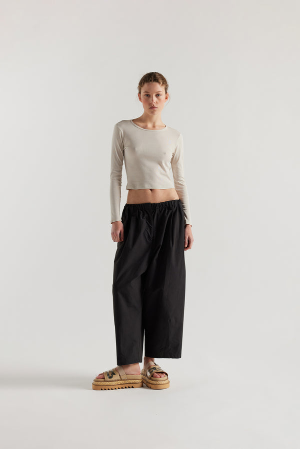 Front view of the model in the Factor Pleat Pant black slate. A relaxed silhouette defined by an encased elastic waistband. 