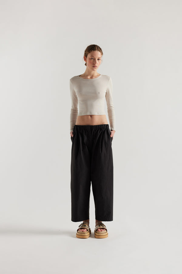 Front view of the model in the Factor Pleat Pant black slate. A relaxed silhouette defined by an encased elastic waistband. 