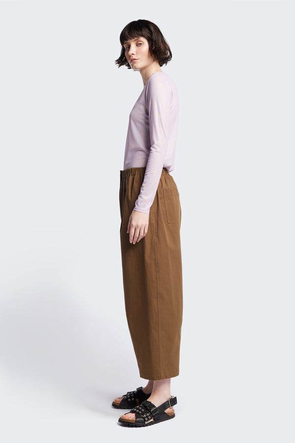 Side of the Factor Pleat Pant in Brown. A relaxed-fit pants with an encased elastic waistband, darted hem detail, side entry pockets, and back patch pockets. Comfortable and perfect for summer. Available in 6 sizes. 