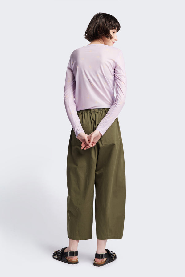 Back view of the model in the Factor Pleat Pant Olive Green. A relaxed silhouette defined by an encased elastic waistband. 