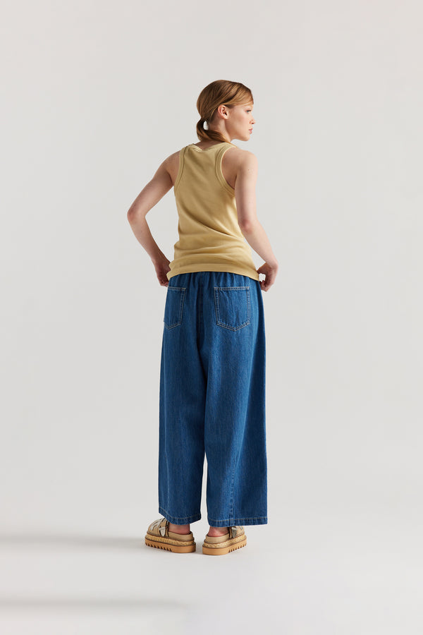 Back of Model wearing slim-fit Japanese ribbed cotton racer-back tank in Pale Yellow. 