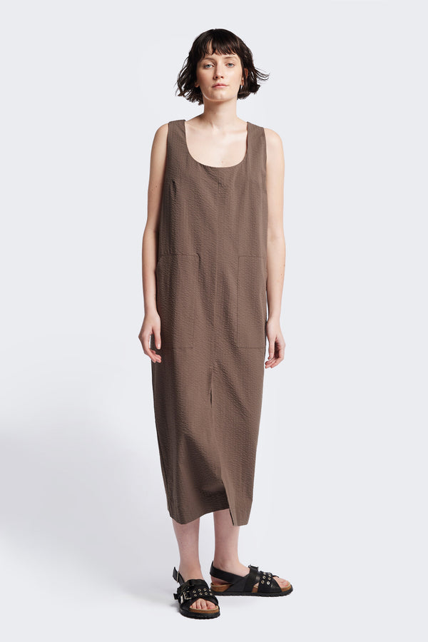 Long-length Forces Pinafore Dress in brown Kloke designed soft seersucker premium cotton . Relaxed fit with a deep rounded neckline, front patch pockets, and a front split for ease of movement. Available in 5 sizes. 