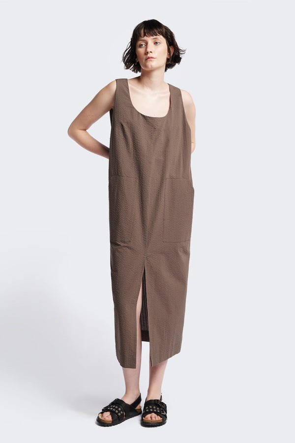 Long-length Forces Pinafore Dress in brown Kloke designed soft seersucker premium cotton . Relaxed fit with a deep rounded neckline, front patch pockets, and a front split for ease of movement. Available in 5 sizes. 