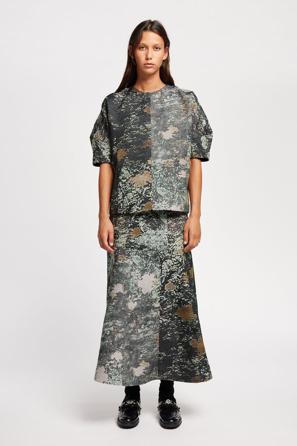 Front of the model in the forge top in green print featuring a unique woven jacquard fabric with real tree camouflage pattern, sculptured panelled sleeves, and a contemporary fit