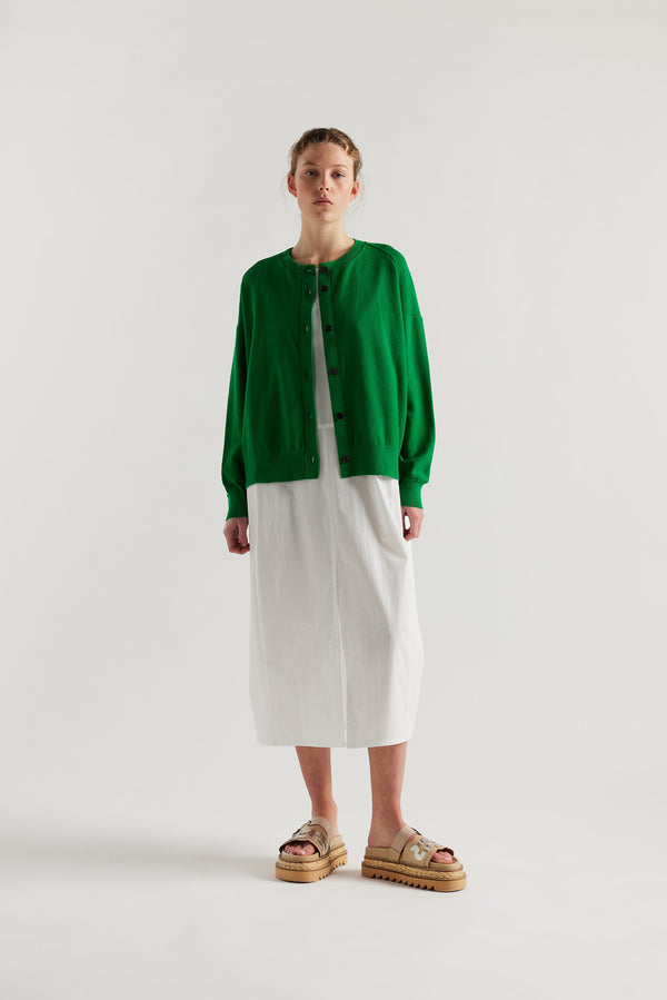 Front view of model in the green cotton ribbed sweater with button closure and dropped shoulders.