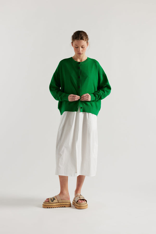 Front view of model in the green cotton ribbed sweater with button closure and dropped shoulders.