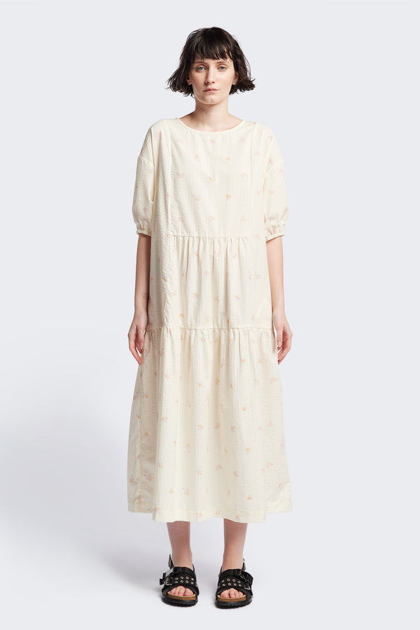 Front of the Gradient Dress in Ecru, a panelled dropped sleeve dress in Kloke's floral seersucker print, featuring a tiered gathered skirt, in-seam pockets, and elastic cuff sleeves.  