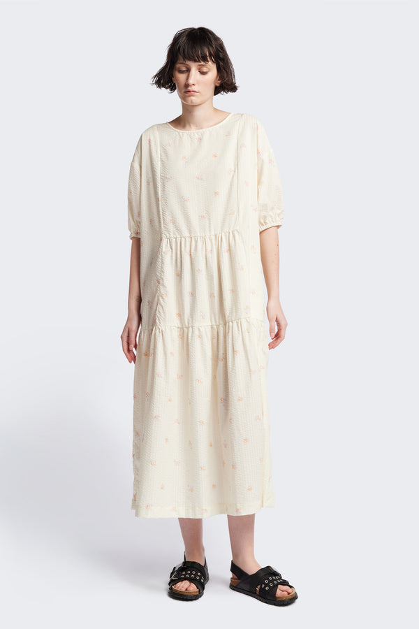 Front of the Gradient Dress in Ecru, a panelled dropped sleeve dress in Kloke's floral seersucker print, featuring a tiered gathered skirt, in-seam pockets, and elastic cuff sleeves.  