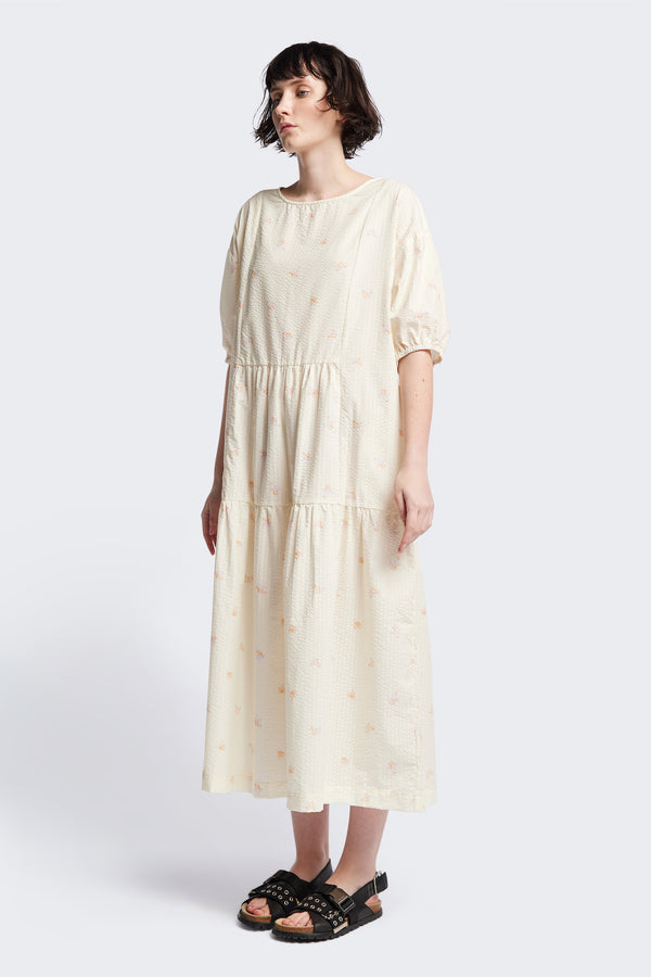 Front of the Gradient Dress in Ecru, a panelled dropped sleeve dress in Kloke's floral seersucker print, featuring a tiered gathered skirt, in-seam pockets, and elastic cuff sleeves.  