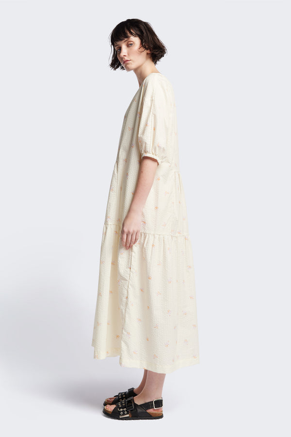 Side of the Gradient Dress in Ecru, a panelled dropped sleeve dress in Kloke's floral seersucker print, featuring a tiered gathered skirt, in-seam pockets, and elastic cuff sleeves.  
