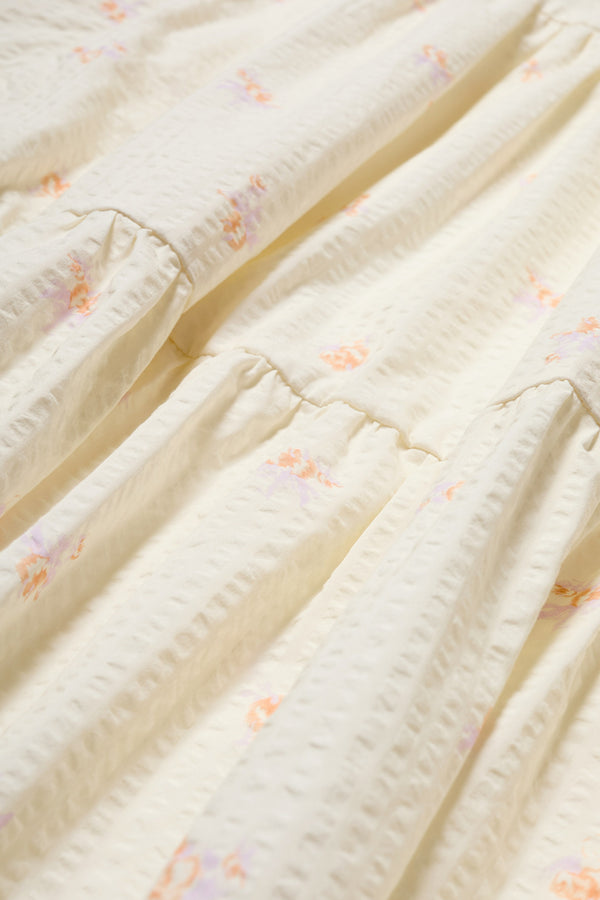 Fabric Details of the Gradient Dress in Ecru, a panelled dropped sleeve dress in Kloke's floral seersucker print, featuring a tiered gathered skirt, in-seam pockets, and elastic cuff sleeves.  