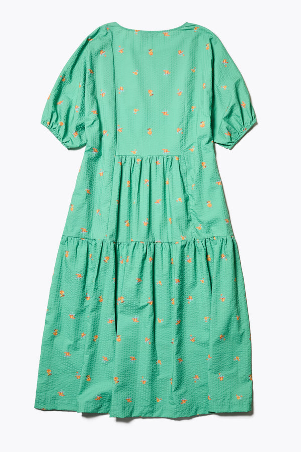Flat back of the Gradient Dress in Green, a panelled dropped sleeve dress in Kloke's floral seersucker print, featuring a tiered gathered skirt, in-seam pockets, and elastic cuff sleeves.  