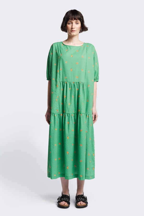 Front of the Gradient Dress in Green, a panelled dropped sleeve dress in Kloke's floral seersucker print, featuring a tiered gathered skirt, in-seam pockets, and elastic cuff sleeves.  