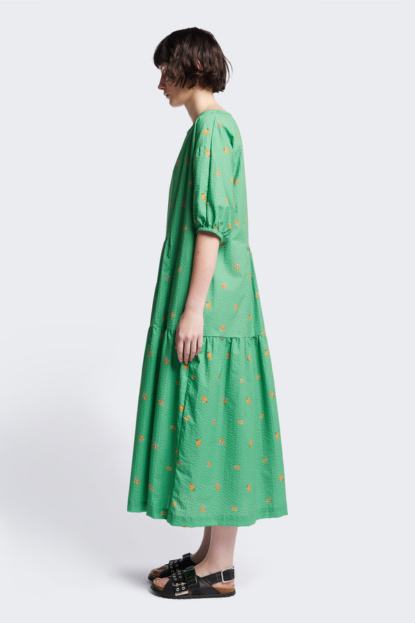 Side of the Gradient Dress in Green, a panelled dropped sleeve dress in Kloke's floral seersucker print, featuring a tiered gathered skirt, in-seam pockets, and elastic cuff sleeves.  