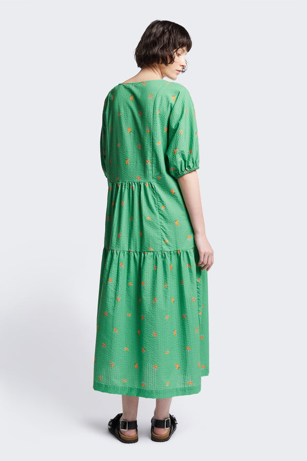 Back of the Gradient Dress in Green, a panelled dropped sleeve dress in Kloke's floral seersucker print, featuring a tiered gathered skirt, in-seam pockets, and elastic cuff sleeves.  