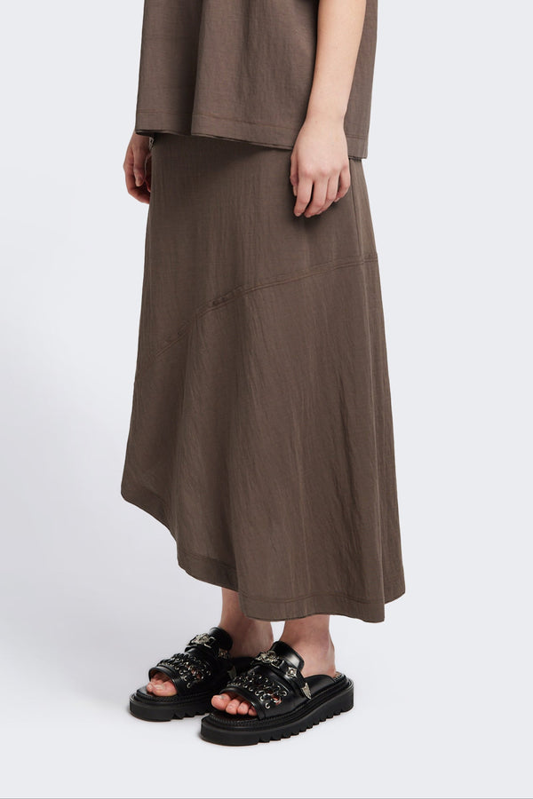 Front of The in time skirt in Taupe brown, an Asymmetrical skirt with panelled detailing, subtle layered effect, and raw hemline, designed to elongate the figure with a flattering waist fit.