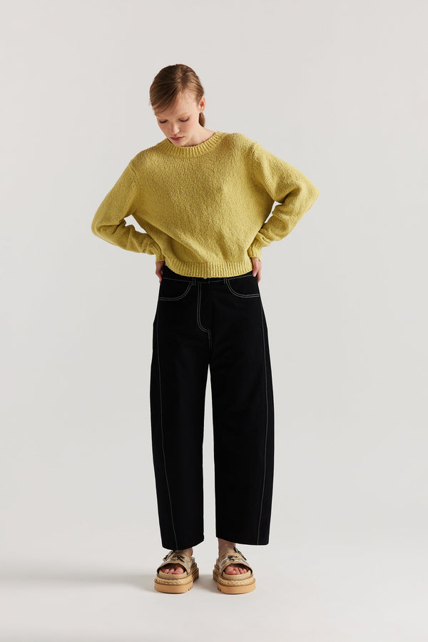 Front of Model wearing tailored cotton pants in black with contrast-stitch front seam panelling.