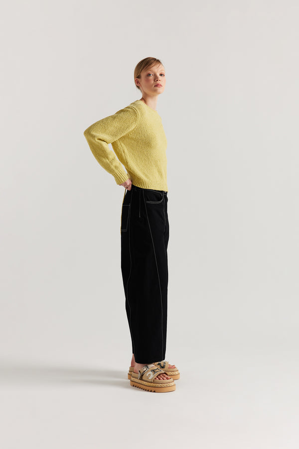 Side of Model wearing tailored cotton pants in black with contrast-stitch front seam panelling.