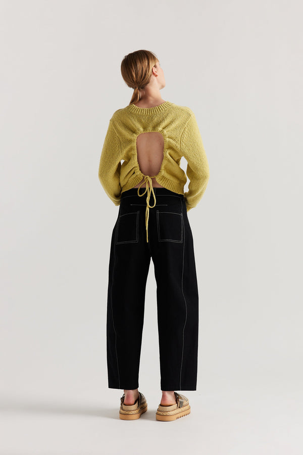 Back of Model wearing tailored cotton pants in black with contrast-stitch front seam panelling.