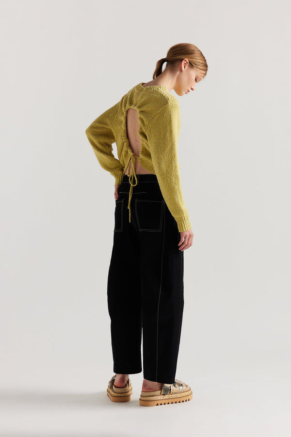 Back of Model wearing tailored cotton pants in black with contrast-stitch front seam panelling.