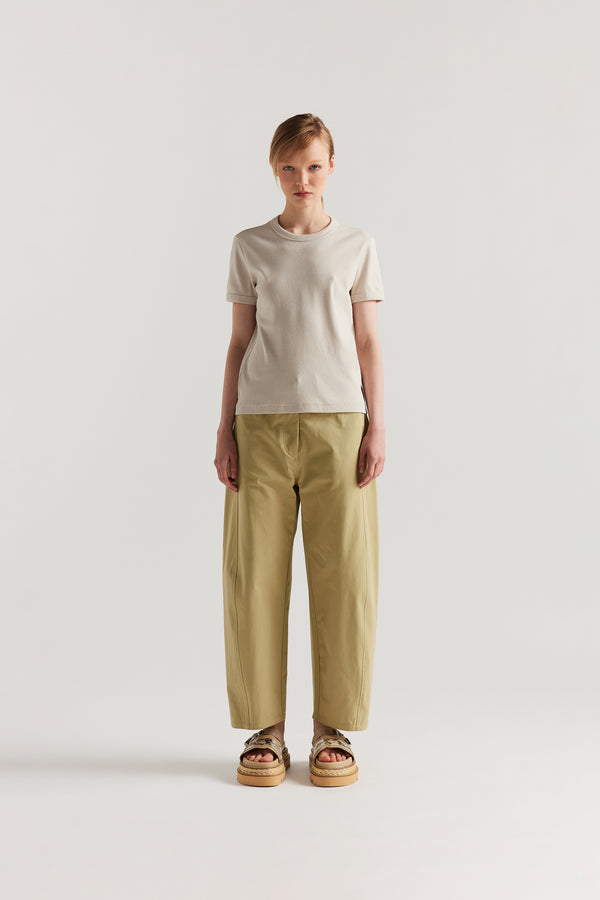 Front of Model wearing tailored cotton pants in sand with contrast-stitch front seam panelling.