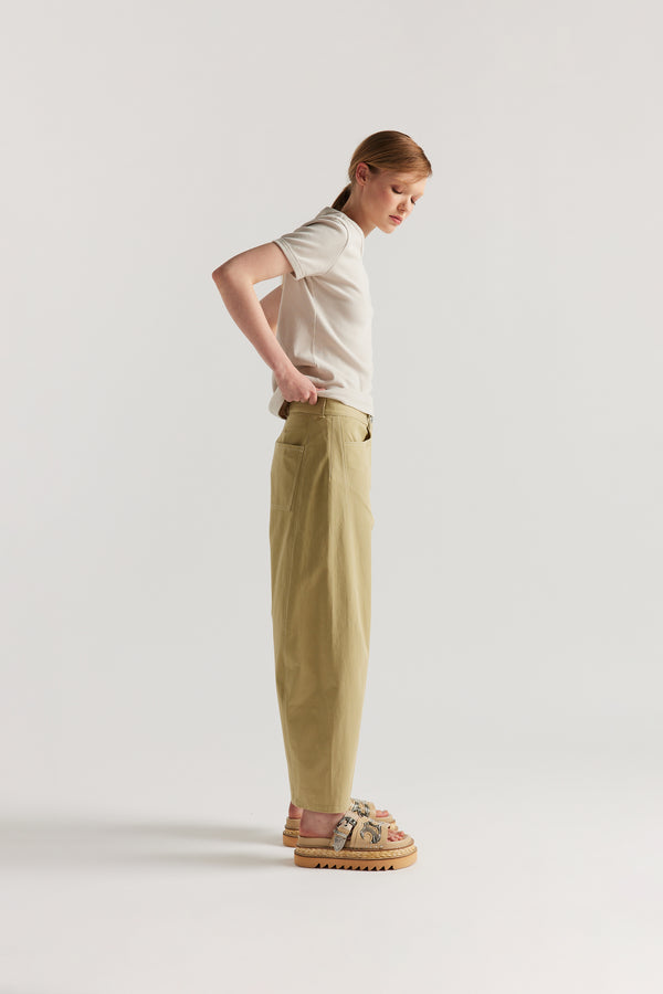 Side of Model wearing tailored cotton pants in sand with contrast-stitch front seam panelling.