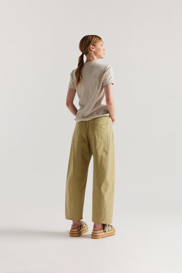 Back of Model wearing tailored cotton pants in sand with contrast-stitch front seam panelling.