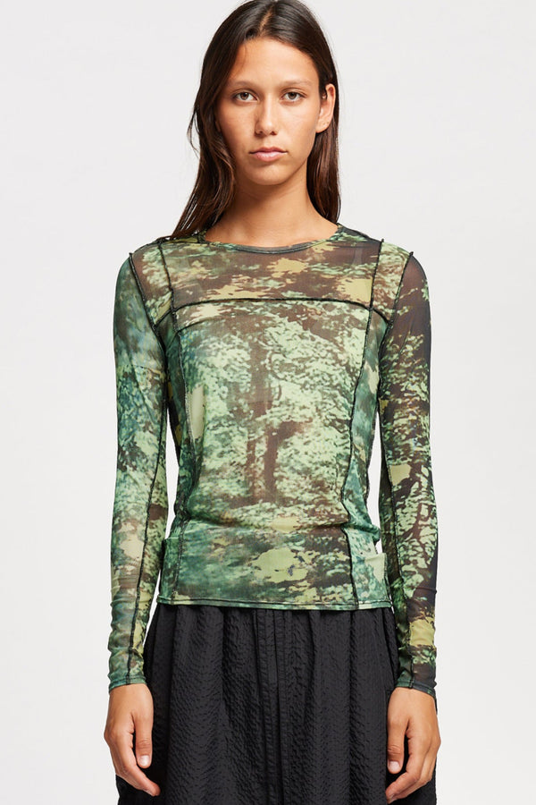 Front view of model in the Inlet Top in Real Tree green print, featuring a slim fit, semi-sheer mesh fabric, and black baby lock stitching.