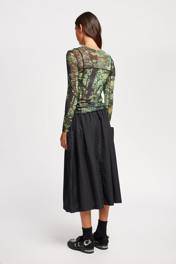 Back view of model in the Inlet Top in Real Tree green print, featuring a slim fit, semi-sheer mesh fabric, and black baby lock stitching.