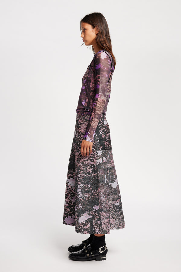 Side view of model in the Inlet Top in Real Tree purple print, featuring a slim fit, semi-sheer mesh fabric, and black baby lock stitching.