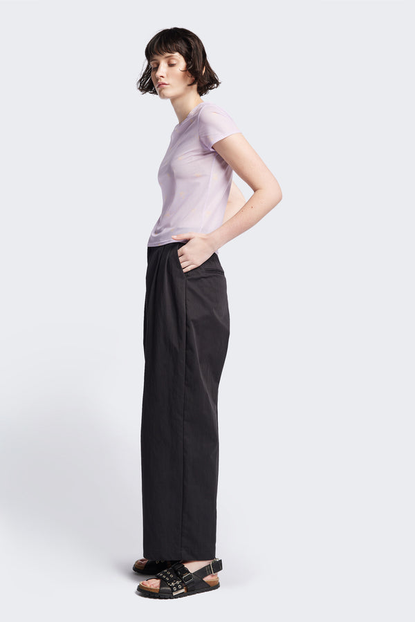 Side of the Interim Pant in Black, Tailored wide-leg in premium cotton with double-front pleats, side slant pockets, jet back pockets, and a hook-and-bar closure. Available in 6 sizes.