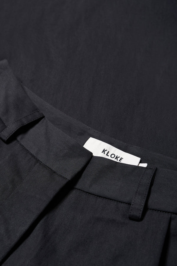 Close up of Fabric for The Interim Pant in Black, Tailored wide-leg in premium cotton with double-front pleats, side slant pockets, jet back pockets, and a hook-and-bar closure. Available in 6 sizes.