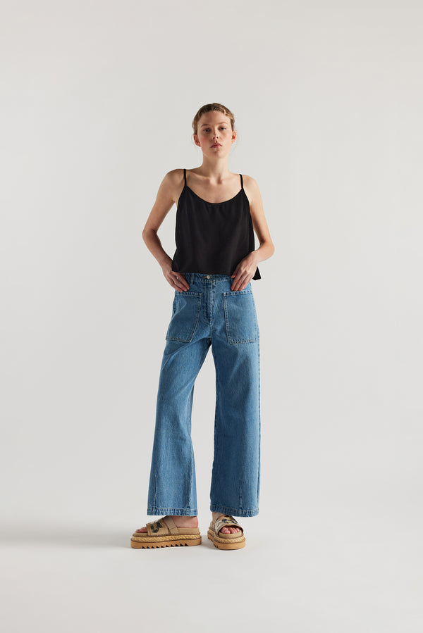Front of female model in the mid blue straight wide-leg denim jeans with a higher-rise waist, patch pockets, and back yoke detail, shown from the front.