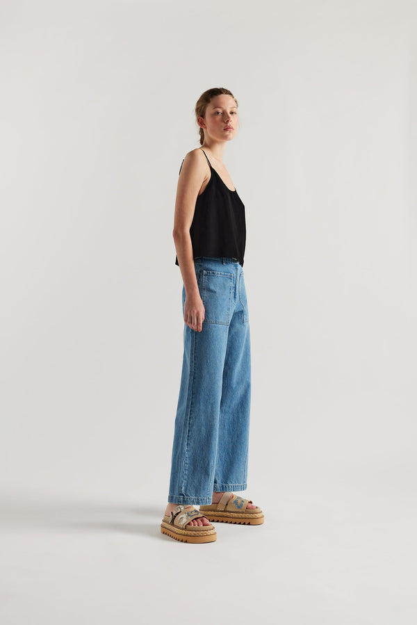 Front of female model in the mid blue straight wide-leg denim jeans with a higher-rise waist, patch pockets, and back yoke detail, shown from the front.