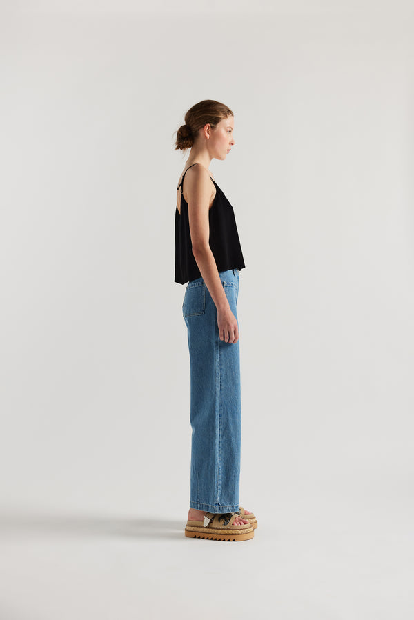 Side of female model in the mid blue straight wide-leg denim jeans with a higher-rise waist, patch pockets, and back yoke detail, shown from the front.