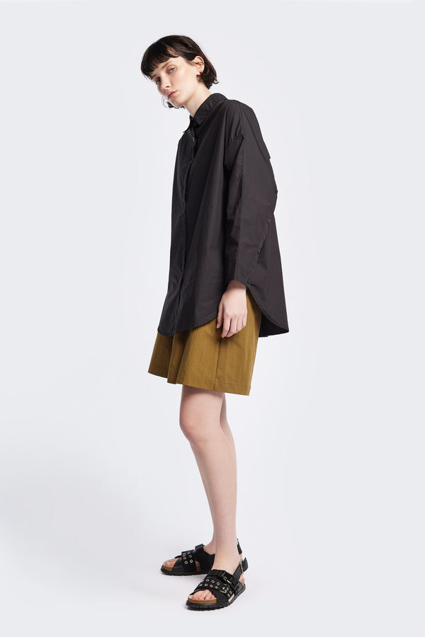 Kestrel Shirt Black – relaxed long sleeve shirt with back button placket and scoop hemline, worn by model. Available in XXS, XS, S, M, L 