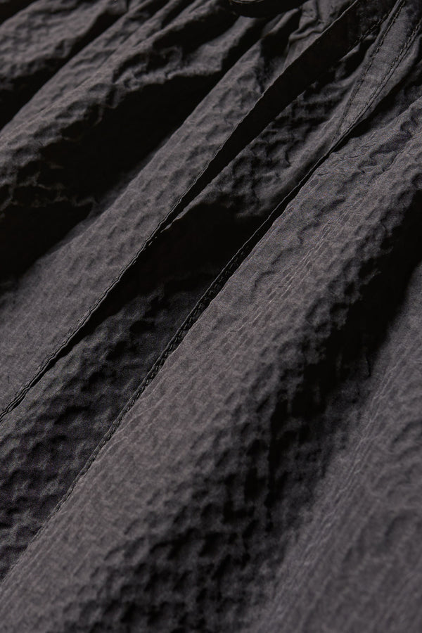 Close up fabric shot of the Jet black Minor Skirt, an A-line midi skirt with an elastic waistband and soft gathered detailing, in lightweight Japanese seersucker.