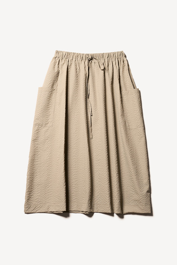 Flat Front of the Stone/Beige Minor Skirt, an A-line midi skirt with an elastic waistband and soft gathered detailing, in lightweight Japanese seersucker.