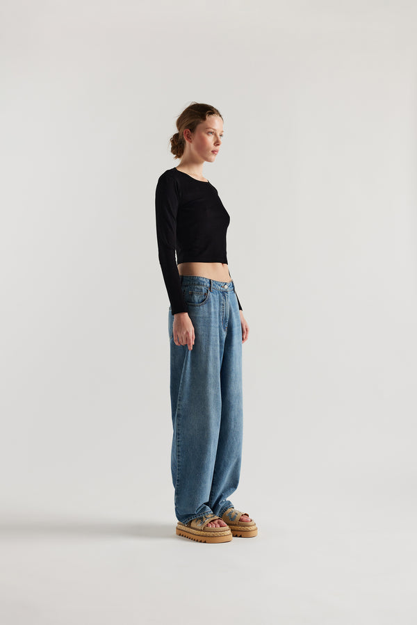 Front angle of female model in the Mist Ballet Top in black, long sleeve silhouette.