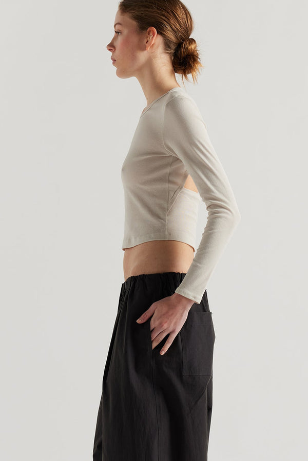 Side of female model in the Mist Ballet Top in bone off white, long sleeve silhouette.