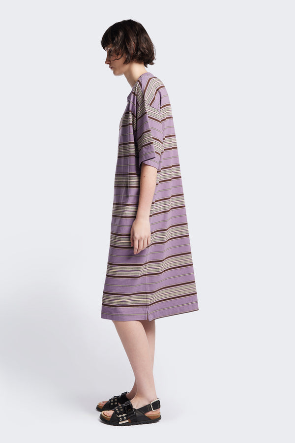 Side of The Nadir Dress in purple stripe, a laid-back style made from pure cotton jersey. This knee-length dress features side-splits, dropped shoulder, and elbow-grazing sleeves. Available in 5 sizes