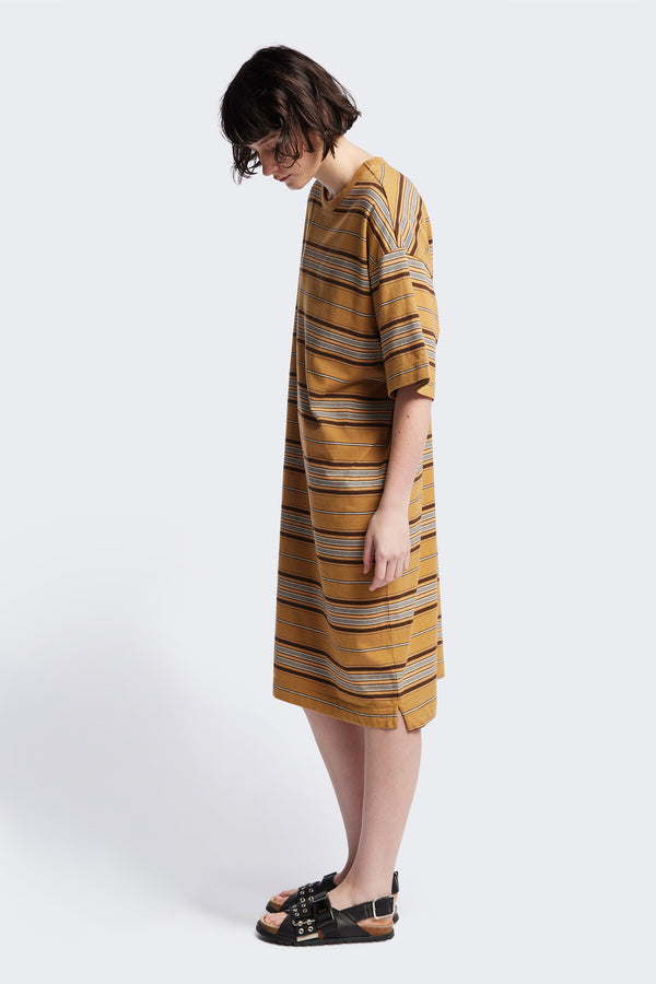 Side of The Nadir Dress in tan stripe, a laid-back style made from pure cotton jersey. This knee-length dress features side-splits, dropped shoulder, and elbow-grazing sleeves. Available in 5 sizes. 