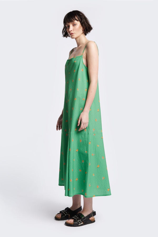 Side of The Natant Dress in green floral, a Maxi-length Natant Dress with adjustable thin straps, a straight neckline, and a bias-cut silhouette, made from lightweight printed seersucker. Available in 5 sizes. 
