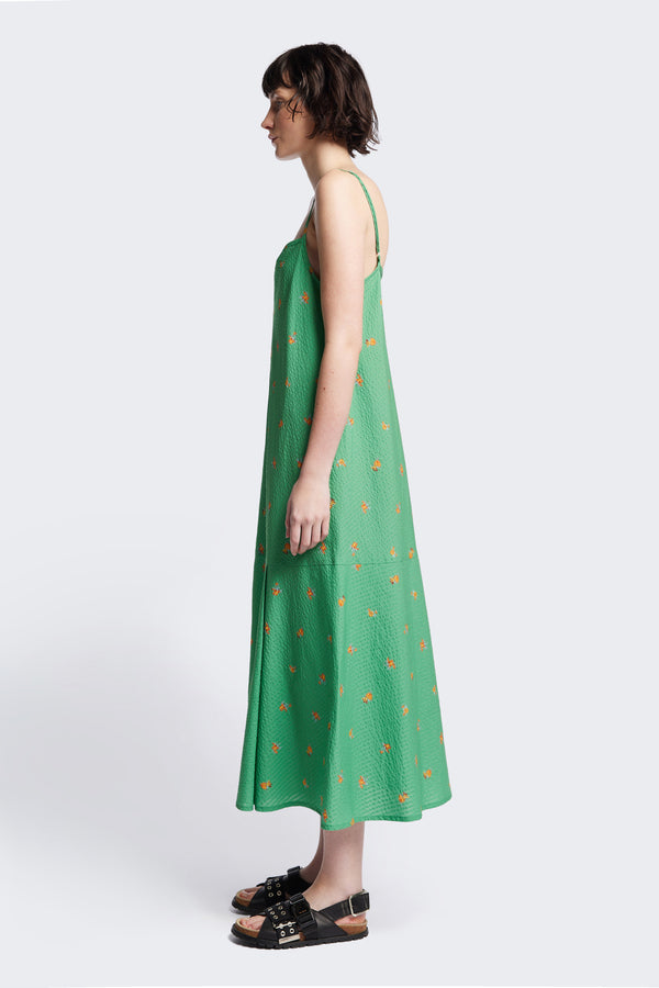 Side of The Natant Dress in green floral, a Maxi-length Natant Dress with adjustable thin straps, a straight neckline, and a bias-cut silhouette, made from lightweight printed seersucker. Available in 5 sizes. 