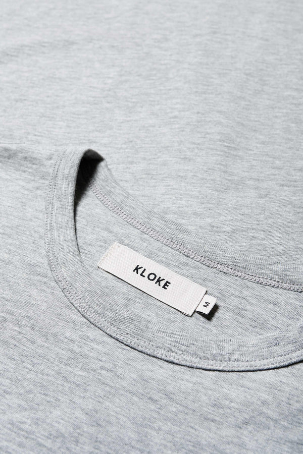 Close up of the Obelisk Tee Grey, A boxy relaxed shape cut in a soft organic cotton jersey, with a thick 1 x 1 rib bound cover stitched neckline and straight hem. Available in 5 sizes.